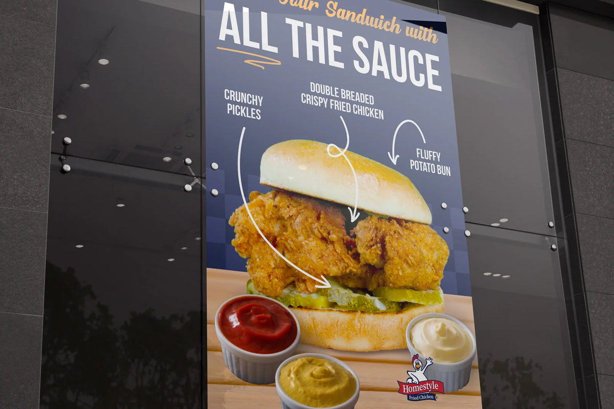 A large vertical restaurant menu poster on a dark glass window, featuring a chicken sandwich with text reading Sandwich with All The Sauce
